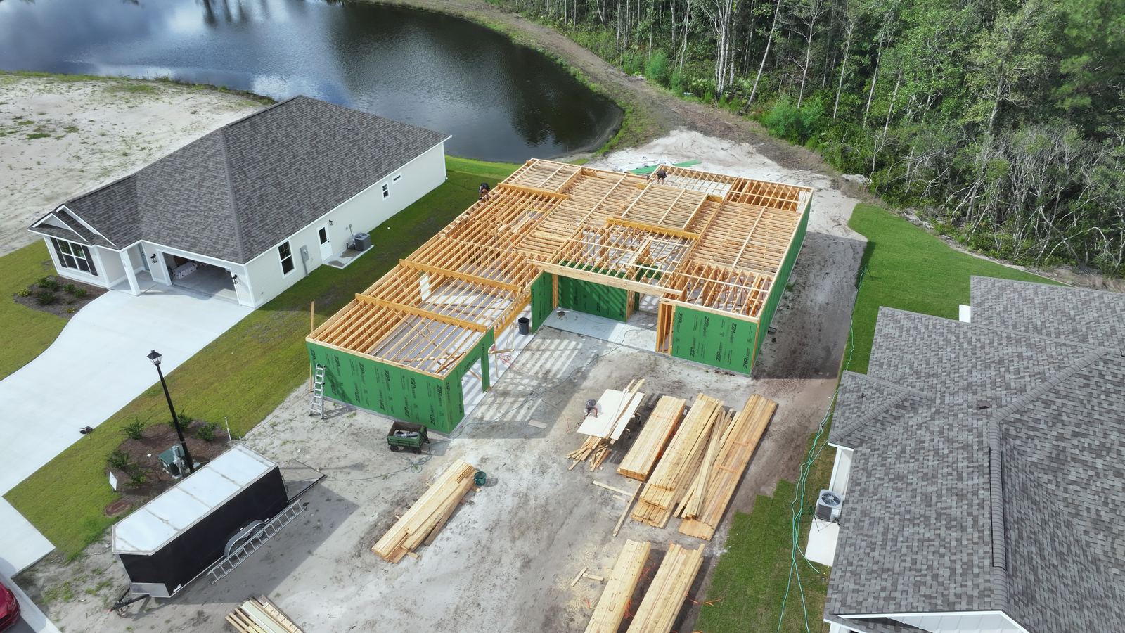 House at the framing stage beside completed homes