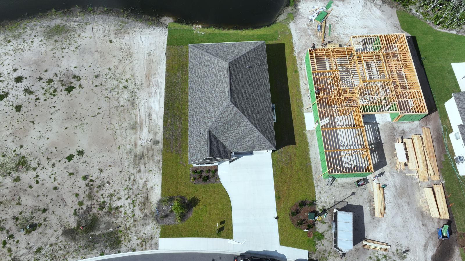 A home at the framing stage beside finished houses